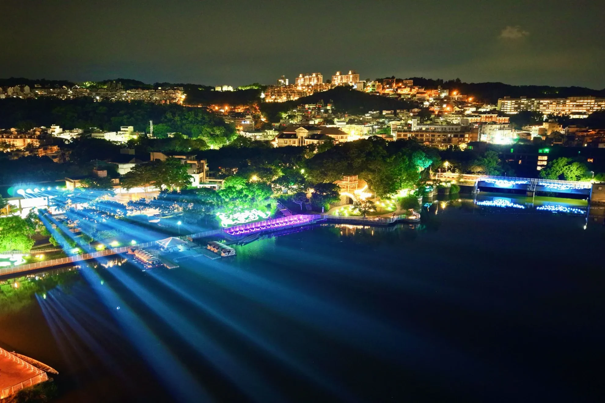 青草湖空拍夜景,藍色展演光束橫越湖面並串聯水岸燈飾