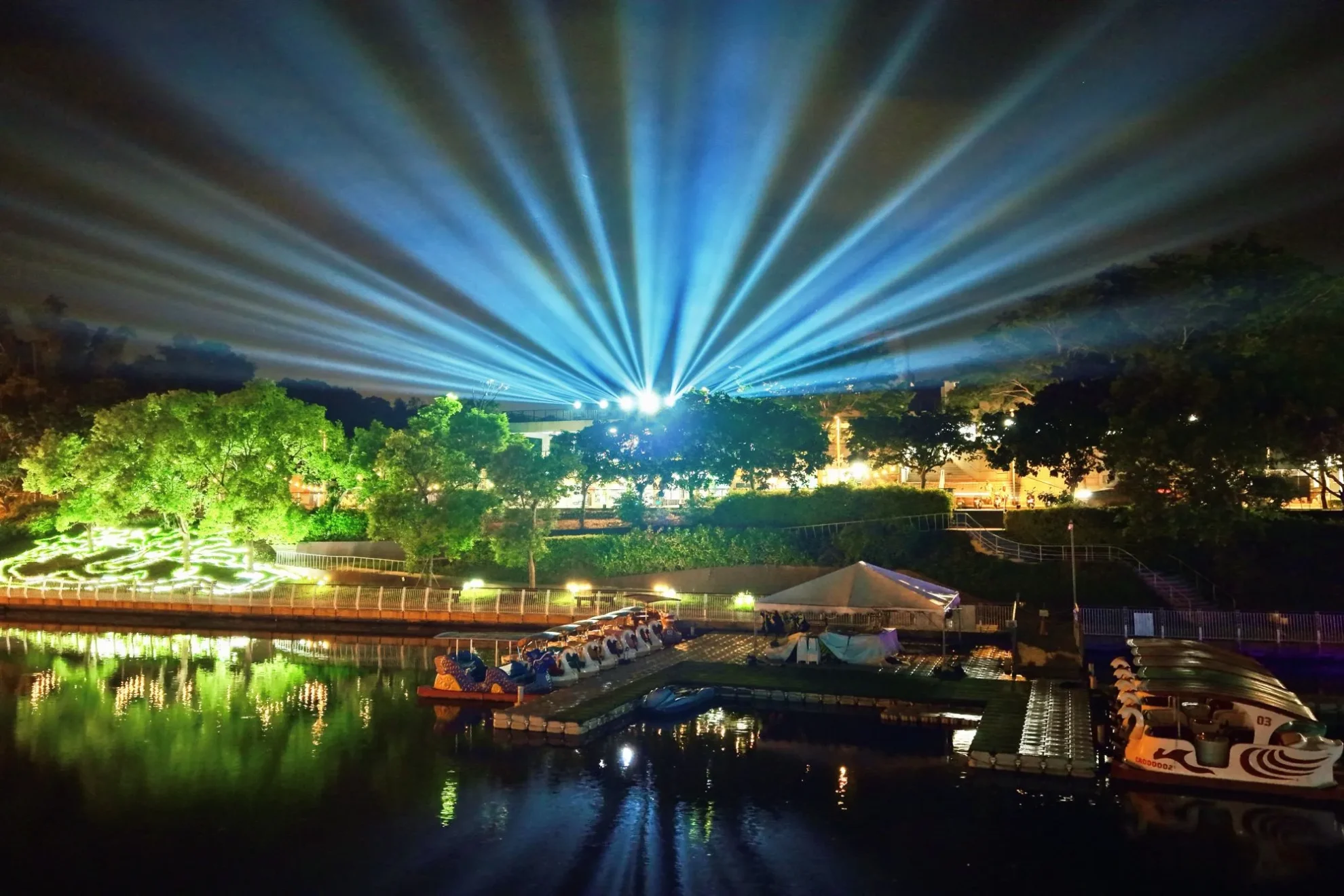 青草湖畔藍色光束向夜空放射,綠色樹林地景與湖面同步映亮