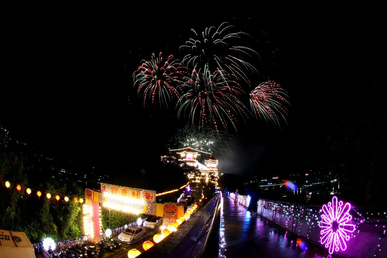 鷄籠中元祭會場紅綠煙火在祭典建築與燈飾步道上空綻放